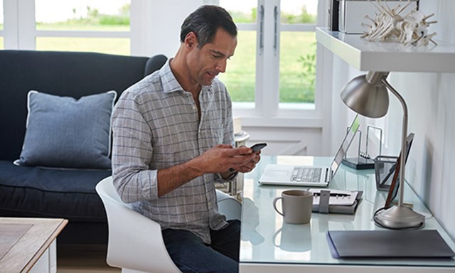 Man working on phone and laptop at home