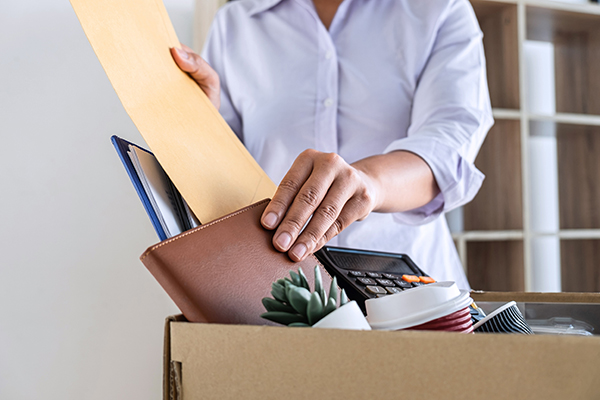Photo of employee leaving job packing belongings from desk into a cardboard box