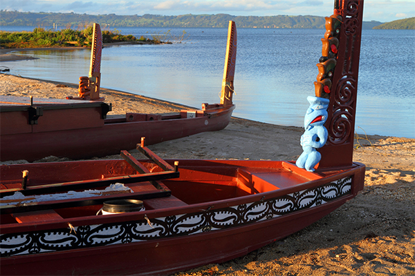 Waka with traditional Māori patterns on lakeshore